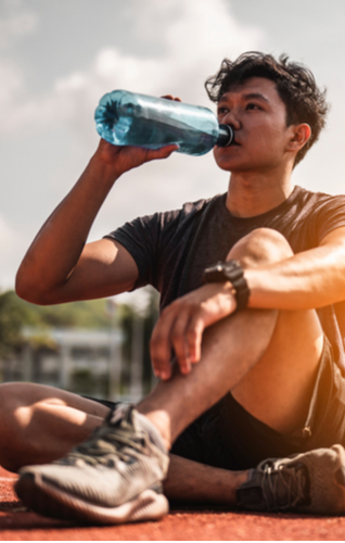 Young man sitting on the floor, drinking water wearing sportswear