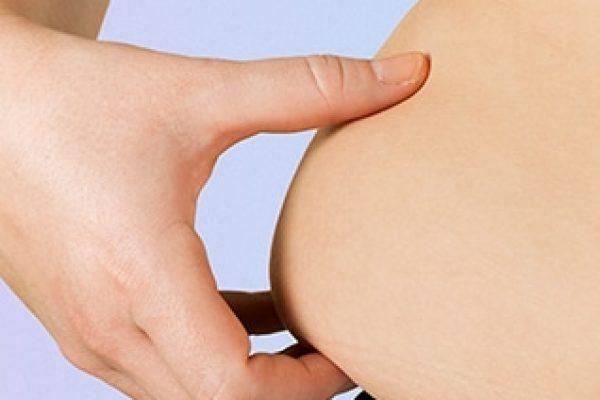 close up of a woman's hand grabbing the Unwanted fat on her waist
