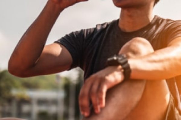 Young man sitting on the floor, drinking water wearing sportswear